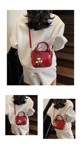 Detail of red glossy bucket bag with metal letters and vintage girl charm on stairs