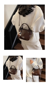 Detail of vintage brown oil wax leather bucket bag with lettering and cute doll pendant