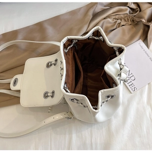 Detail view of the white bucket bag featuring a brown lining with a zippered pocket