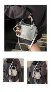 Detail of silver oil wax leather bucket bag with embossed text and cute doll charm