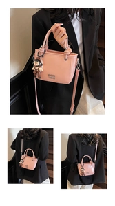 Detail of light pink bucket bag featuring metal COIH 2DN logo and cute cartoon charm