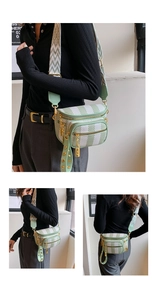 Detail view of mint green plaid canvas crossbody bag with wide geometric strap and gold hardware