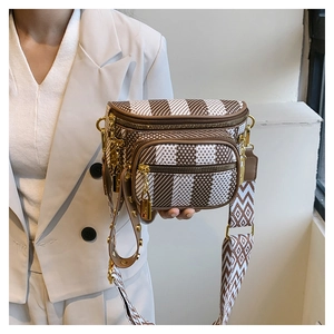 Detail of geometric pattern crossbody bag with wide strap and gold lock charm on white suit
