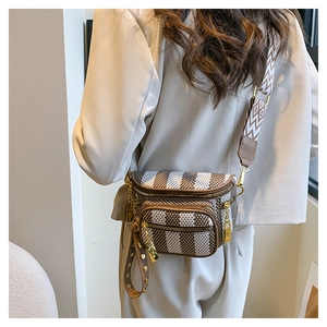 Detail of checkered chest bag with wide geometric strap and golden hardware accents