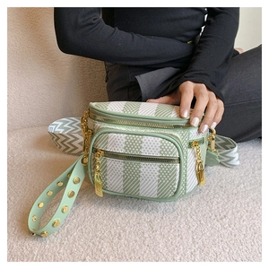 Detail of checkered crossbody bag with gold chain and studded patterned strap