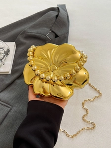 Detail of gold floral evening clutch bag with glossy metallic finish and bead handle