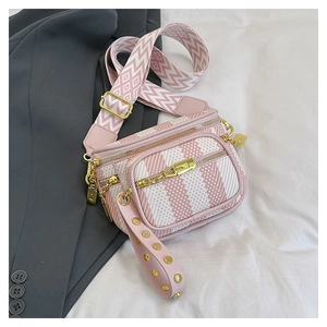 Detail of pink geometric stripe saddle bag with gold zippers and wide shoulder strap