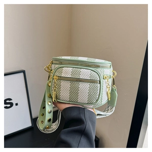 Close-up of green checkered crossbody bag featuring dual gold zippers and wide woven strap
