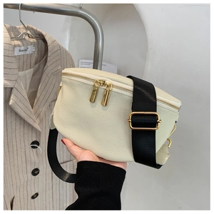 Detail of cream pebbled leather crossbody bag featuring black strap and gold hardware