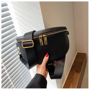 Detailed view of black litchi grain leather bag with dual golden zippers and nylon strap