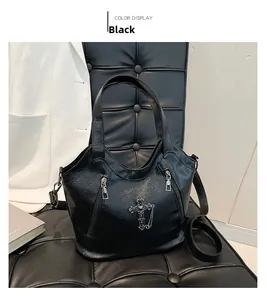 Detail of black pebbled leather tote bag with gothic metal cross and chain accessories