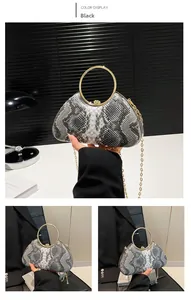 Detail of snake skin print evening bag featuring a gold ring handle and chain strap