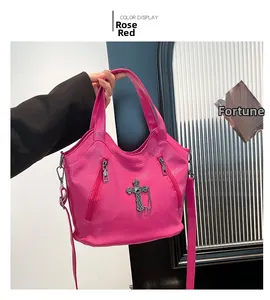 Detail of rose red biker bag with metallic cross charms and textured pebbled leather