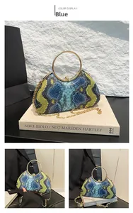 Detail of snake skin pattern handbag with golden metal handle and chic chain strap