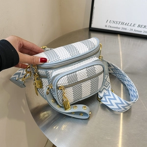 Crossbody chest bag with grey plaid pattern and blue jacquard wide strap on metal desk