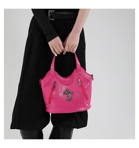 Detailed shot of pink faux leather bag with cross pendant and metal zipper accents