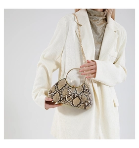 Detail of snake skin pattern evening clutch with round gold handle and metal chain