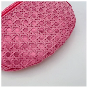 Détail de la pochette en cuir PU rose avec texture tressée et fermeture éclair