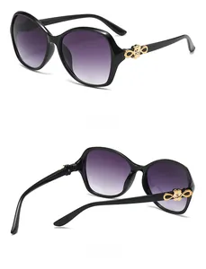 Detail view of large black frame sunglasses with golden hollow flower pattern on temple