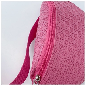 Gros plan sur la texture tissée rose du sac banane en PU avec détail de fermeture