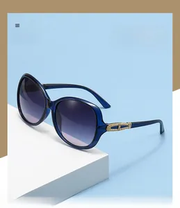 Close-up of blue oversized sunglasses with golden hollowed metal decor and gradient lenses