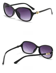 Detail view of large oval sunglasses with purple gradient lenses and gold temple accents