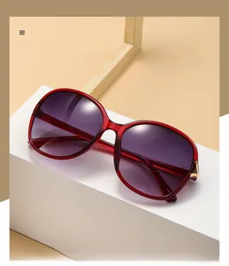 Detail of burgundy sunglasses frame with golden V-shaped metal accent and purple lenses