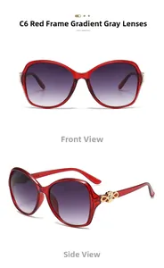 Detail view of red oversized sunglasses featuring golden infinity metal hinges and grey lenses