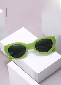Lunettes de soleil œil-de-chat vert citron avec verres foncés sur socle blanc