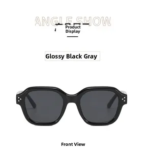 Detailed front view of black wide-frame sunglasses with three-dot metal rivets and grey lenses