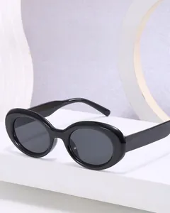 Close-up of black oval resin sunglasses with dark UV lenses on a geometric display