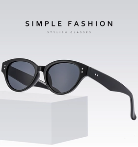 Detailed view of black cat-eye sunglasses with metal rivets on a white geometric stand