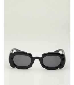Détail de lunettes de soleil noires en forme de fleur avec monture ondulée et verres foncés