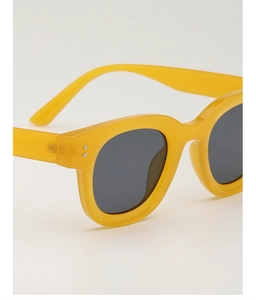 Detailansicht der gelben quadratischen Sonnenbrille mit dunklen Gläsern und Silbernieten