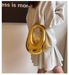 Close-up of golden hollow oval clutch bag with sleek metallic chain and mirror finish