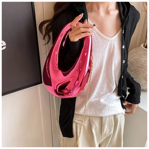 Mirror pink acrylic hard shell clutch bag with gold chain strap shown on a model