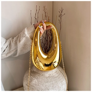 Close-up of a hollow circular gold metallic clutch bag with a sleek chain strap