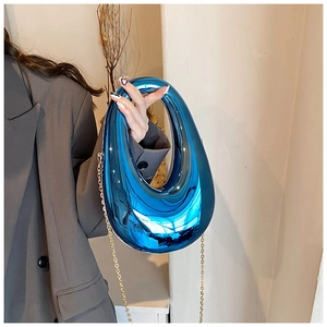 Detail of royal blue mirrored acrylic clutch bag with metallic oval cutout handle