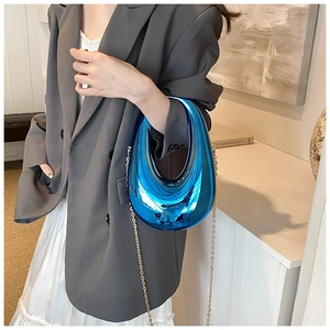 Blue mirror crescent handbag with gold chain strap shown on a modern outfit