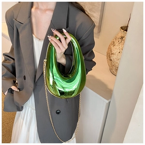 Macro view of metallic green acrylic clutch with gold chain strap and mirror finish