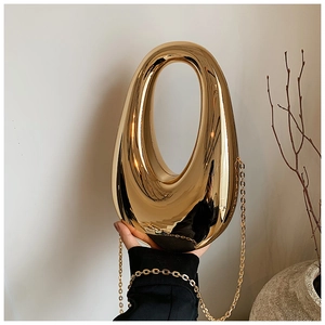 Detail of artistic gold irregular oval clutch bag with high-polish mirror finish and chain