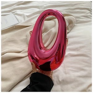 Macro shot of metallic fuchsia acrylic box bag with gold chain and round top handle