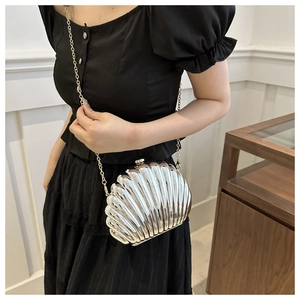 Detailed view of silver shell-shaped evening bag with a delicate gold chain strap