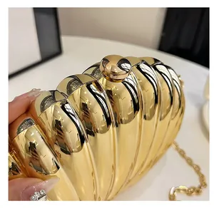 Detailed view of glossy gold shell evening clutch with radial pleats and metal ball clasp