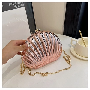 Macro view of metallic rose gold shell clutch with radial texture and gold chain strap