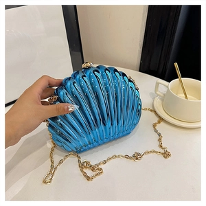 Detail of candy-colored shell clutch bag with glossy blue finish and gold chain strap