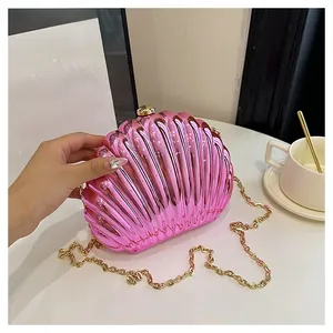 Detail of pink candy shell clutch bag with gold ball clasp and chain on table