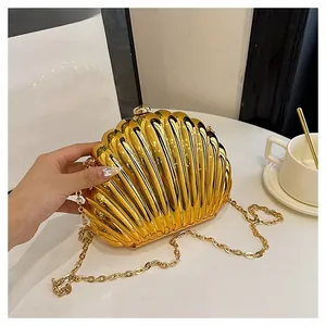 Detailed close-up of shell-shaped gold party clutch with elegant vertical ribbing and metal chain