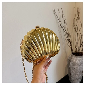 Detail of a gold shell evening clutch featuring radiant textures and a metallic chain strap