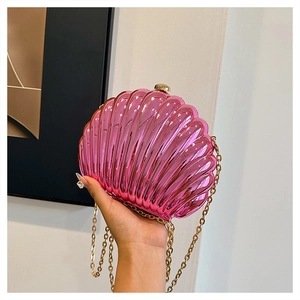Detailed view of fuchsia shell clutch bag with metallic finish and gold chain strap